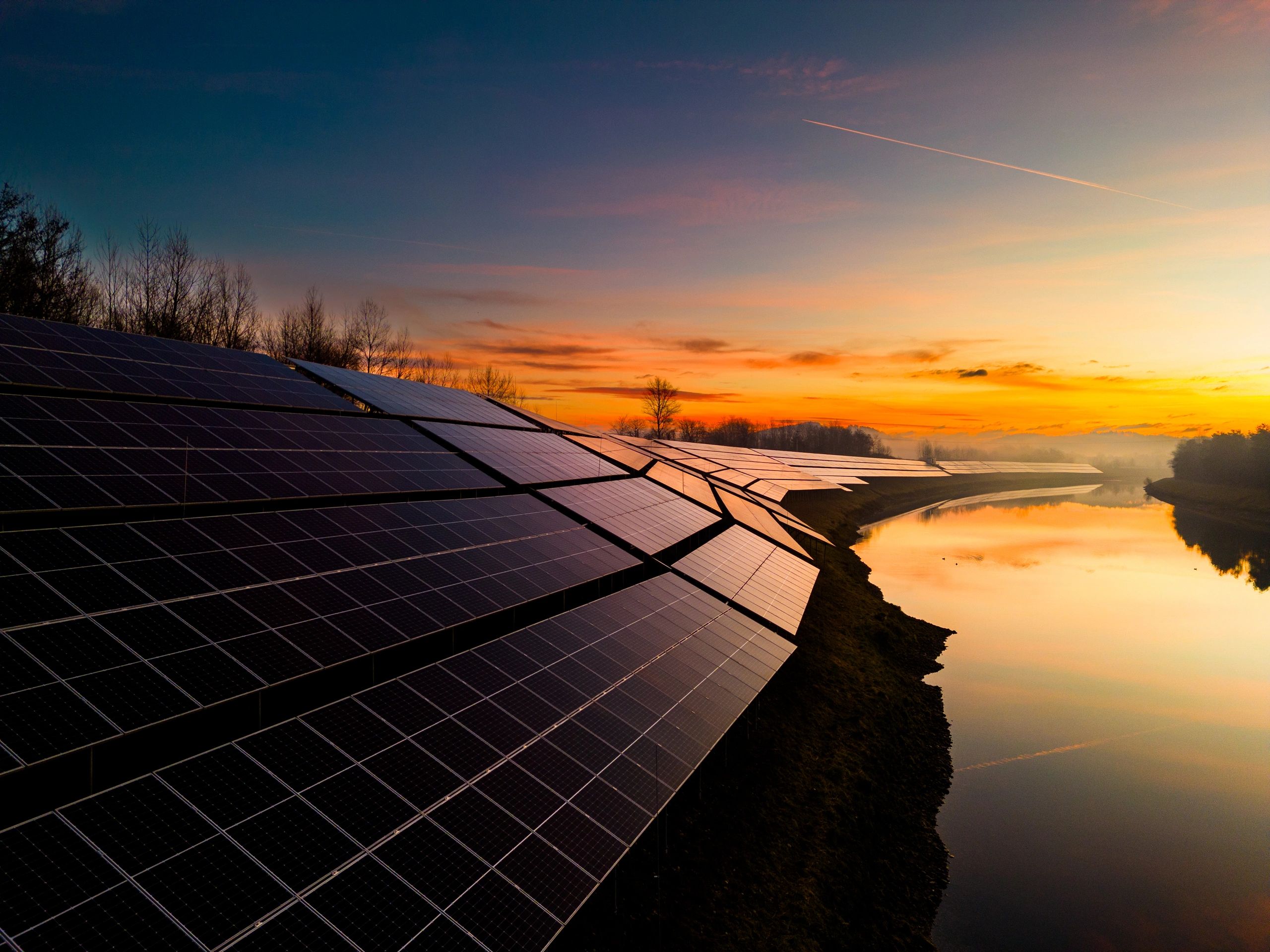 Solar panels near a river at sunset