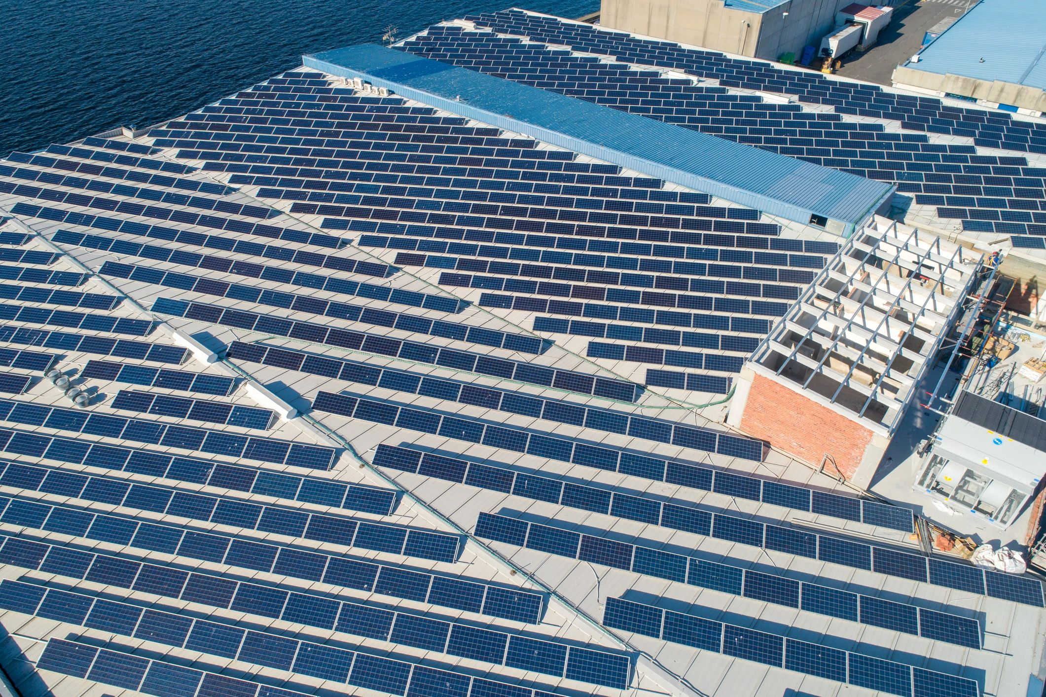 Rooftop solar panels generating clean energy for a large industrial building near ocean